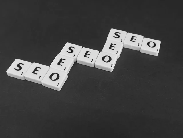SEO spelled with Scrabble tiles on a black surface, representing search engine optimization concepts. Søgemaskineoptimering: sådan opbygger du synlighed over tid